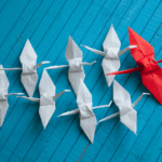 Paper birds, with a red one leading the pack